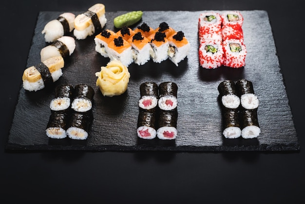 A set of different sushi rolls with caviar on black background