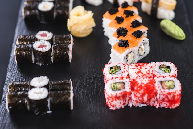 A set of different sushi rolls with caviar on black background