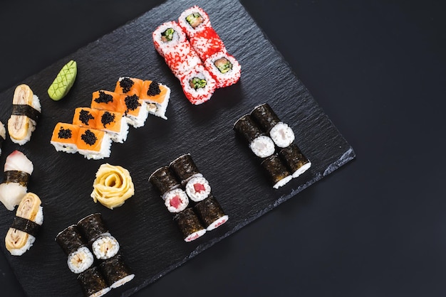 A set of different sushi rolls with caviar on black background