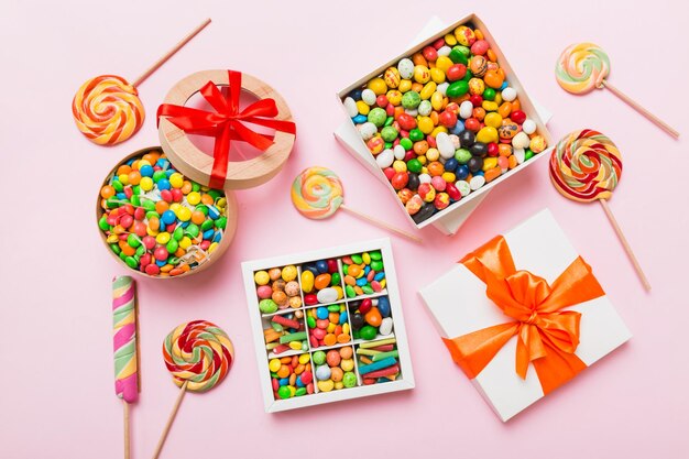 Photo set of different sweet candy in a paper box with a satin ribbon on a colored background holiday concept