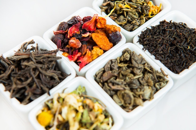 Set of different tea in bowls on white background