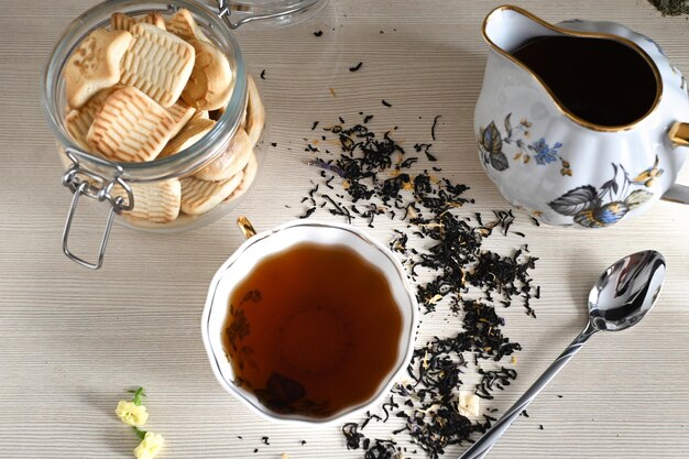 ベージュの背景に熱い淹れたお茶で満たされたやかんの横にあるさまざまな種類のお茶のセット