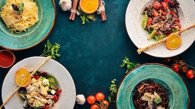 A set of dishes Pasta with parmesan cheese and vegetable salad and blue cheese Top view Free space for your text On a wooden background