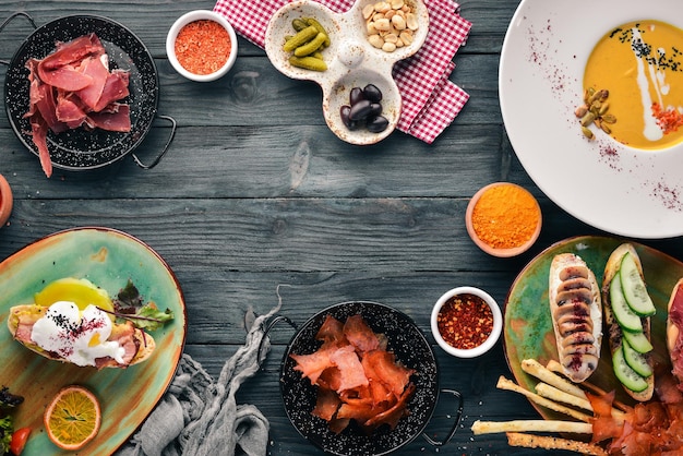 A set of dishes Pumpkin soup avocado sandwich prosciutto and mushrooms Top view Free space for your text On a wooden background