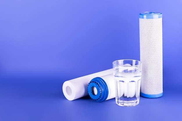 Set drie patronen voor waterfilter met helder glas water geïsoleerd op violette achtergrond