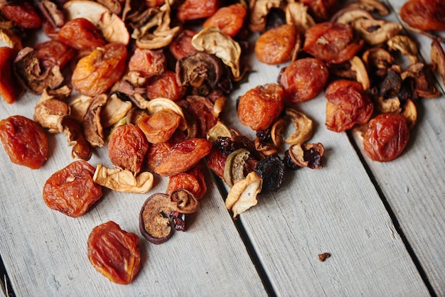 Set of dried fruits of apples, apricots and raisins lying on a wooden table closeup