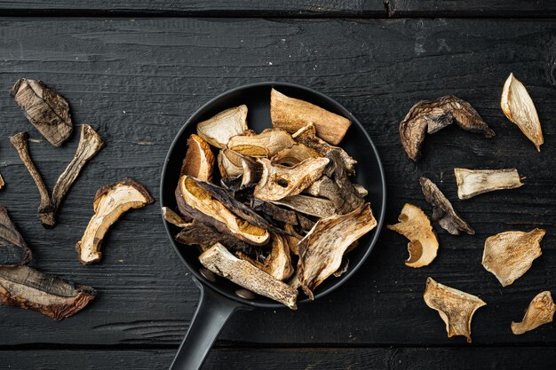 Set of dried mushrooms set, on black wooden table background, top view flat lay