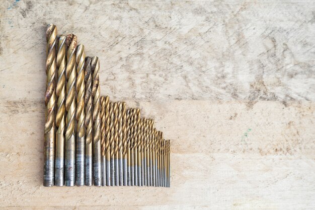 Set of drills of different size on a wooden background. Top view