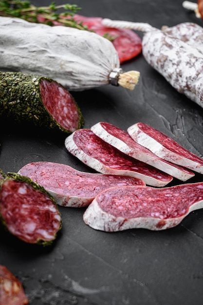 Set of dry cured salami, spanish sausages, slices and cuts on black background