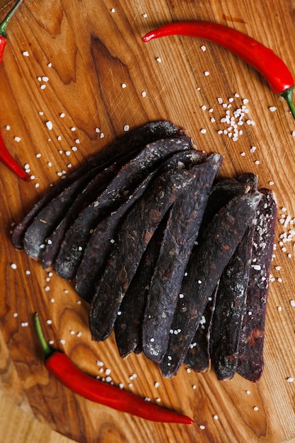 Photo a set of dry meat with spices and red pepper on a wooden tray view from above