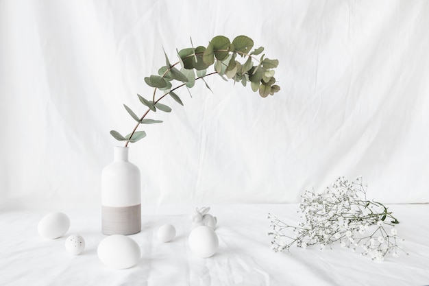 Set of Easter eggs near plant branch in vase and flower twigs