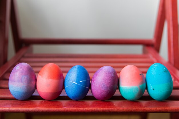 Set of easter eggs standing on red chair background. colorful festive bright eggs abstractly painted blue, pink, green and purple.