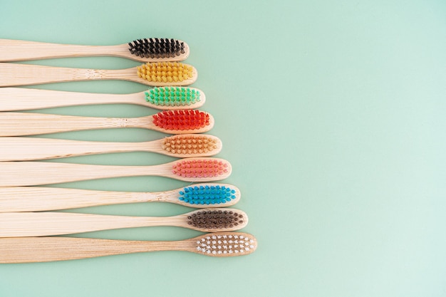 A set of Eco-friendly antibacterial toothbrushes made of bamboo wood on a light green background.