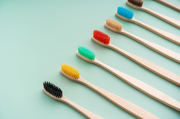 A set of Eco-friendly antibacterial toothbrushes made of bamboo wood on a light green surface