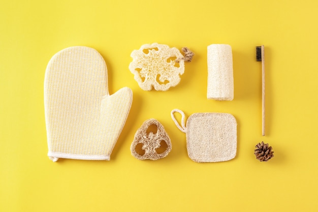 set of eco friendly bathroom accessories, tools for bath, natural bamboo toothbrush, sponge. zero waste cosmetics products on yellow.