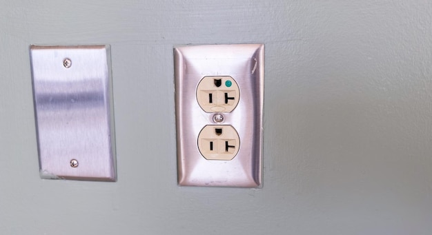 Photo a set of electrical outlets with a green switch in the middle.