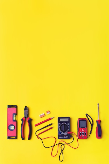 Set of electrician's tools on yellow background. Flat lay composition with electrician's tool