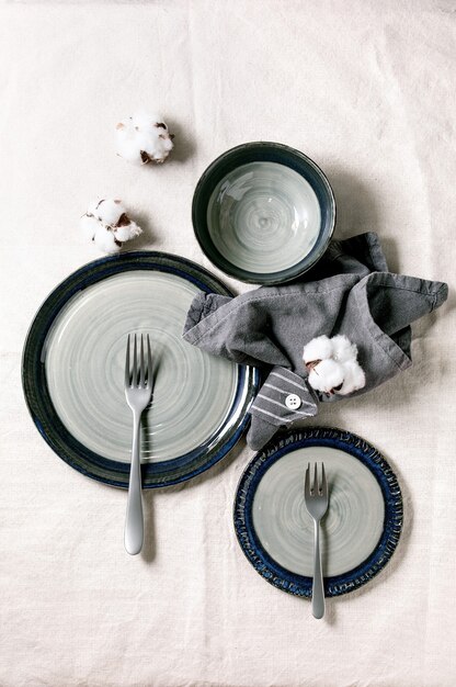 Set of empty gray ceramic plates with forks and textile napkin