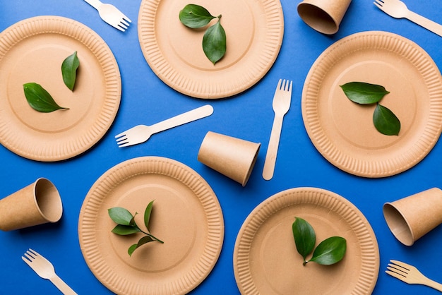 Set of empty reusable disposable eco-friendly plates, cups, utensils on light white colored table background. top view. Biodegradable craft dishes. Recycling concept. Close-up