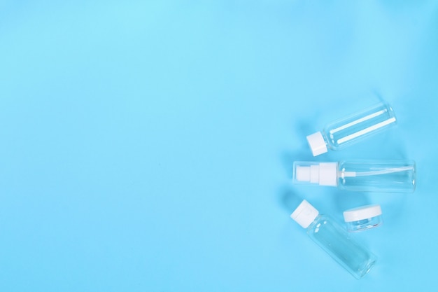 Set of empty small traveling cosmetics bottles on blue background. 