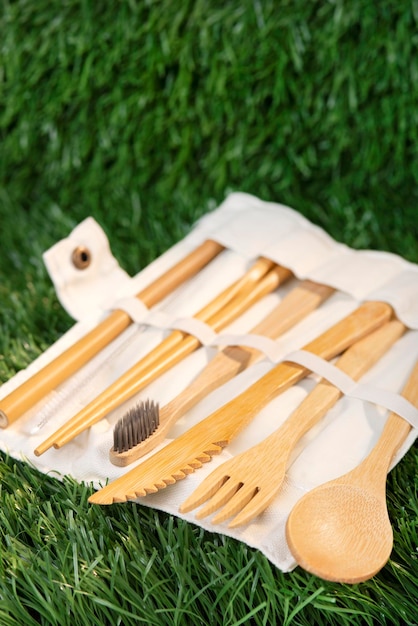 A set of environmentally friendly bamboo cutlery on a green grass background in a case.