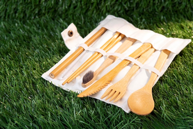 A set of environmentally friendly bamboo cutlery on a green grass background in a case.