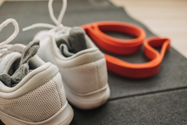 Комплект спортивной обуви с резинкой и тренировочный коврик на полу