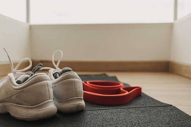 Set of exercise shoes rubber band and workout mat on the floor