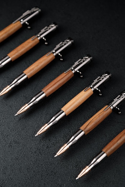 A set of expensive military pens made of rare wood compositions\
on a dark background luxury gift pen