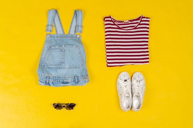 Set of female clothes and accessories on bright yellow background