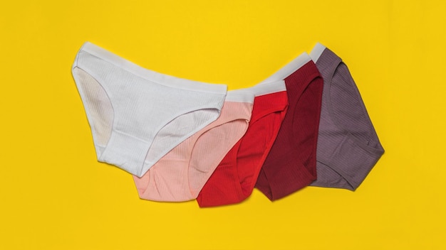 A set of five colored panties on a yellow background Minimal concept of women's underwear