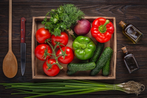 Set of fresh salad products. Fresh vegetables in a wooden box, a bottle of olive oil and balsamic vinegar