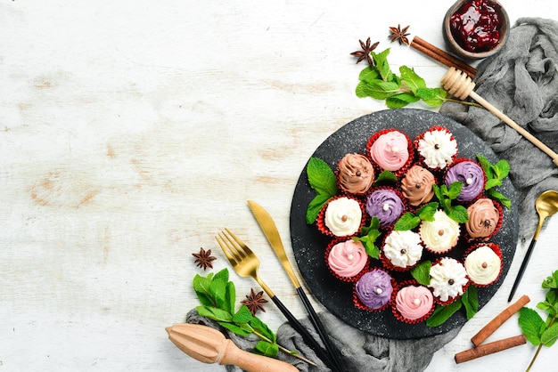 Set gekleurde roommuffins op een zwarte plaat met munt Bovenaanzicht Rustieke stijl