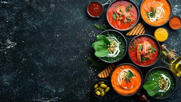 Set gekleurde soepen Spinaziesoep Tomatenroomsoep en wortelpureesoep Gezonde voeding Op een zwarte stenen achtergrond