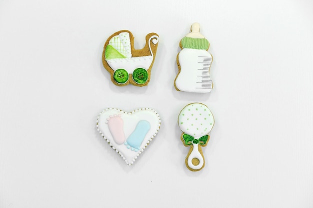 Set of gingerbread in the form of a baby stroller a bottle a rattle and a heart on a white background Vaby birthday gift Top view