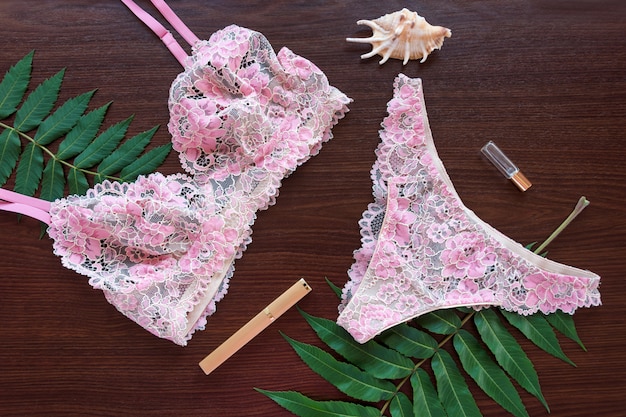 Set of glamorous stylish sexy lace lingerie lying on dark wood with flowers