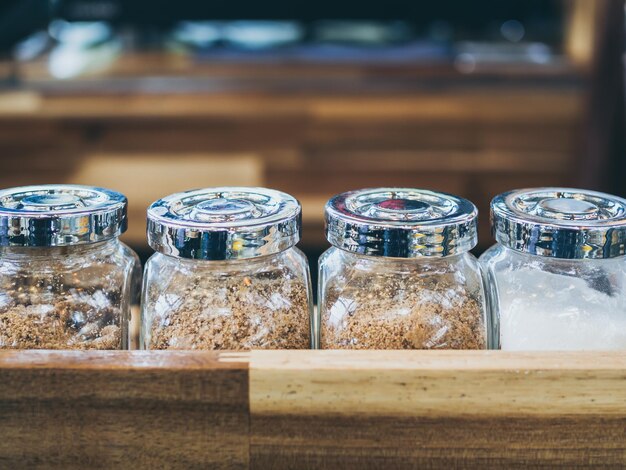 Photo set of glass bottle of sugar on wooden shelf