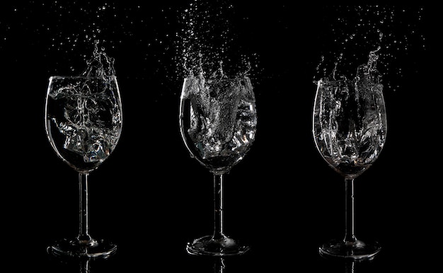 Set of glasses with water splash on a black background