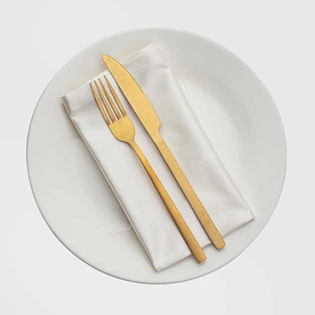 白いナプキンと皿に金製の食器セット