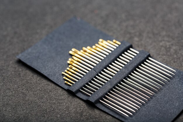 Set of Gold needles on a black background in a row.