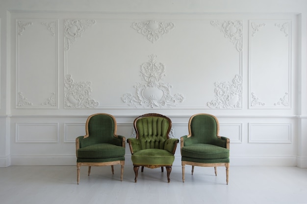 Set of green wooden vintage chairs standing in front a white wall