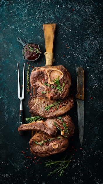 Set of grilled steaks on a black stone table with spices and herbs Top view Free space for your text