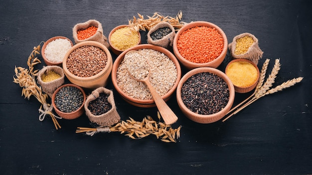 Set of Groats and Grains Buckwheat lentils rice millet barley corn black rice On a black background Top view Copy space