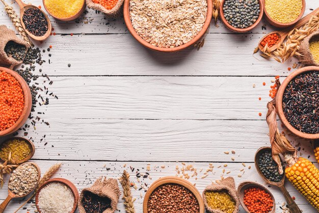 Set of Groats and Grains Buckwheat lentils rice millet barley corn black rice On a white wooden background Top view Copy space