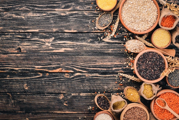 Set of Groats and Grains. Buckwheat, lentils, rice, millet, barley, corn, black rice. On a wooden  background. Top view. Copy space.