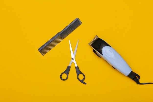 Set of hairdresser (barber) on a yellow background. Hair clipper, scissors and comb. Top view. Flat lay