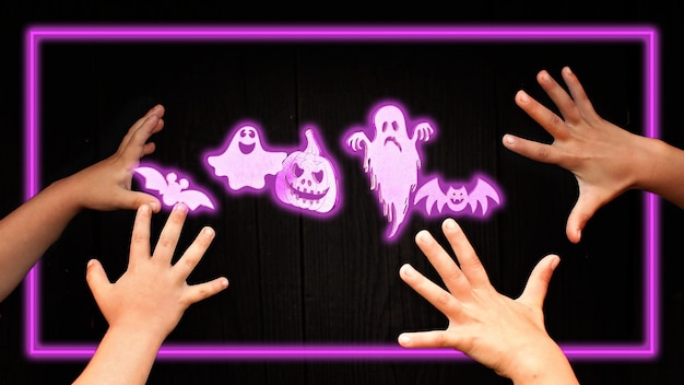 Set of halloween neon halloween symbols for holiday party.
lightening trendy scary pumpkin, spider, bat, ghost and mummy over
dark wooden background and kids hands, focus on holiday
symbols