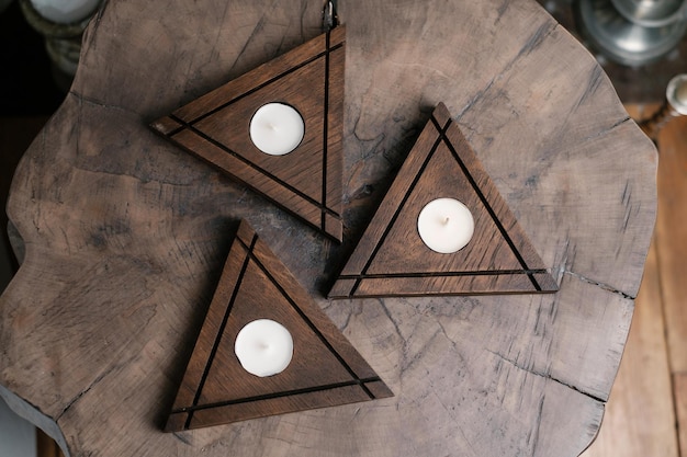 A set of handmade dark brown triangular wooden candlesticks