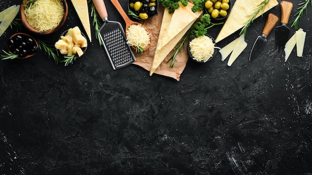 set of hard cheeses with cheese knives on black stone background parmesan top view free space for your text