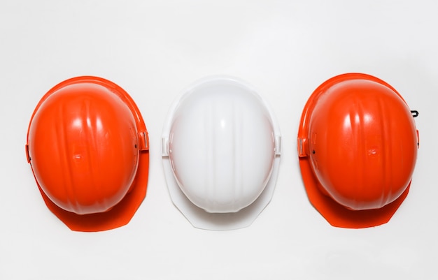 Photo set of hard hats. two orange and one white.